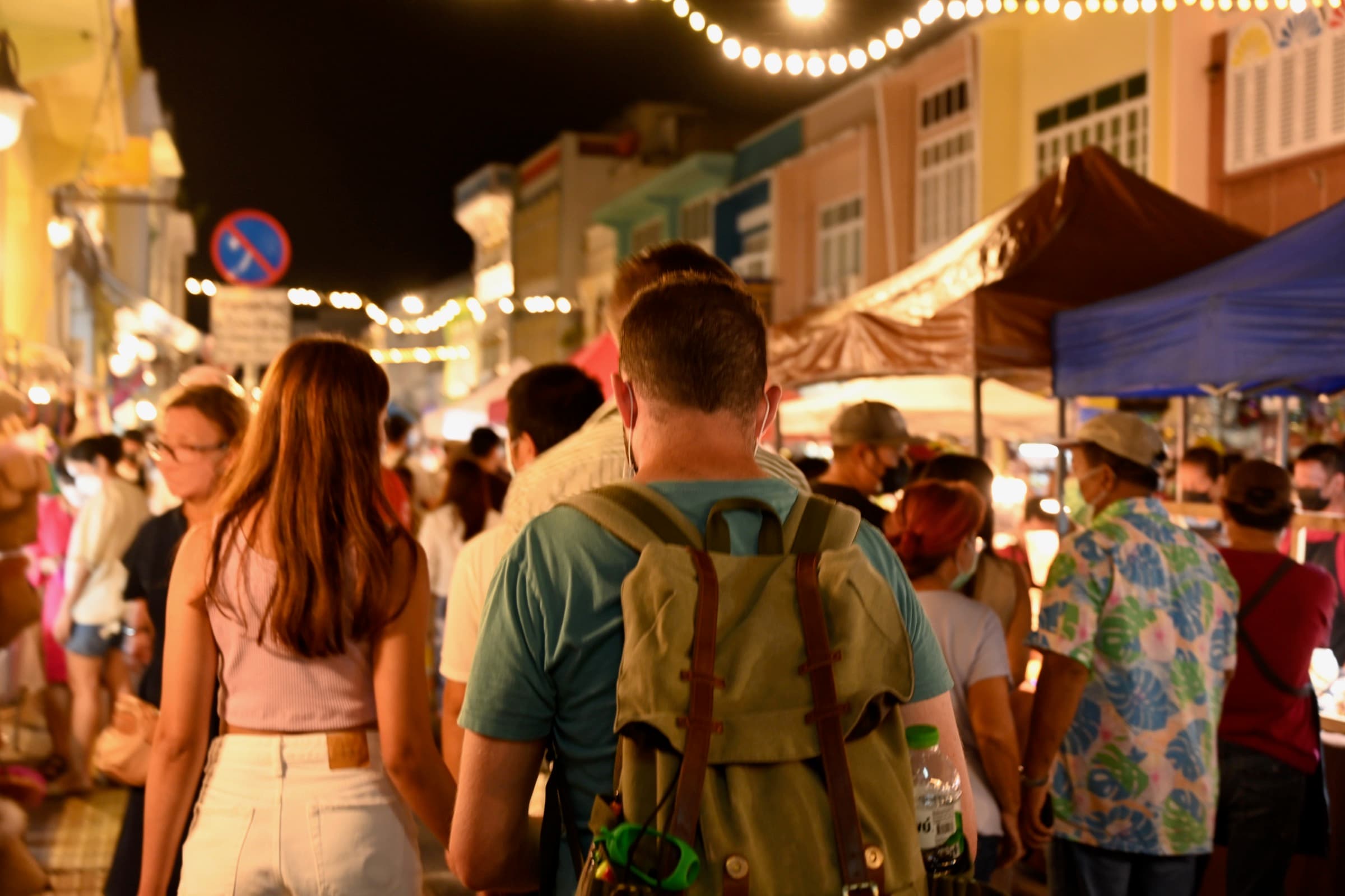 Crowds moving through a night market in Thailand beneath warm stall lights.