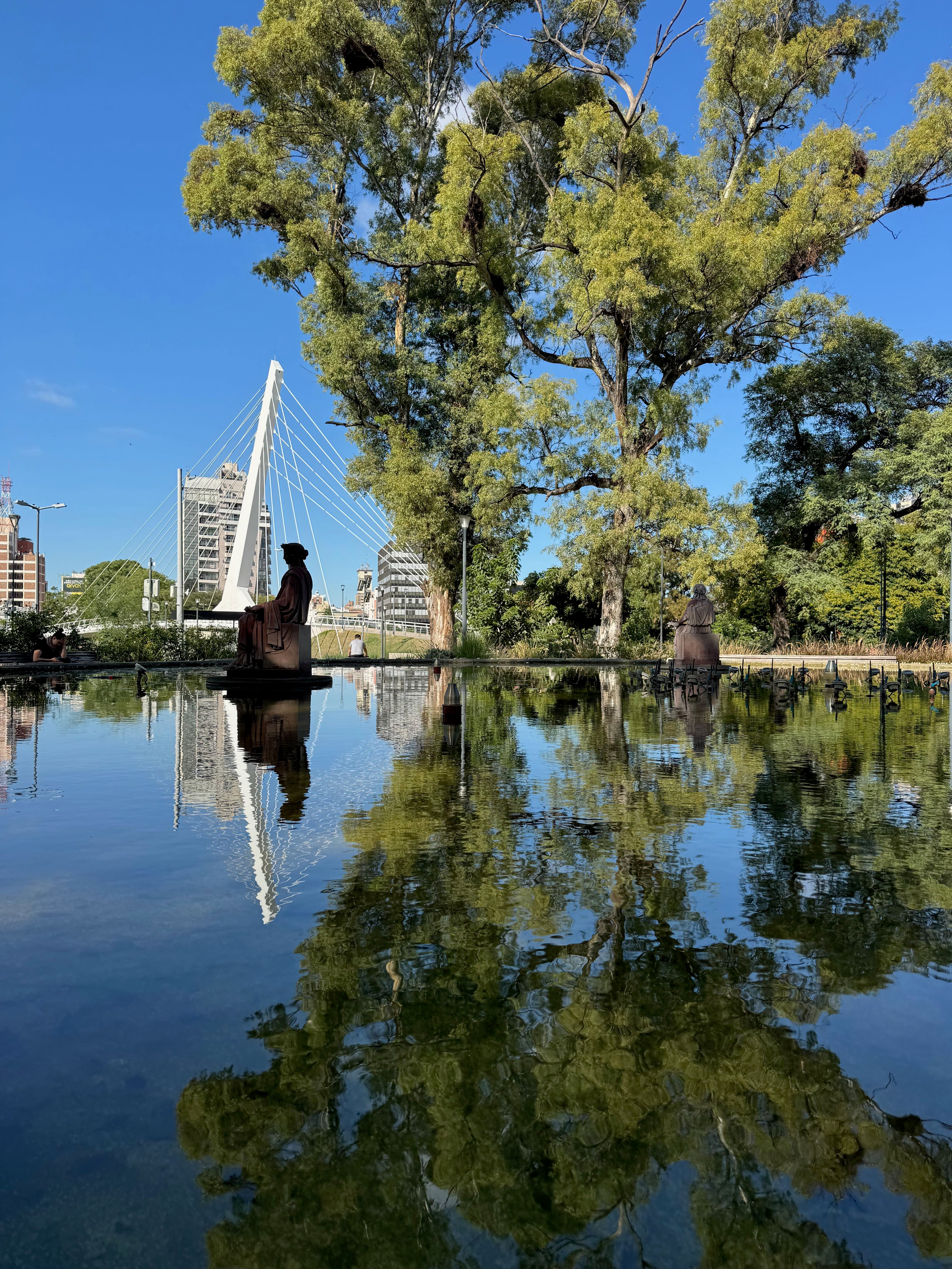 Reflecting pool with a footbridge and trees in central Córdoba, Argentina.