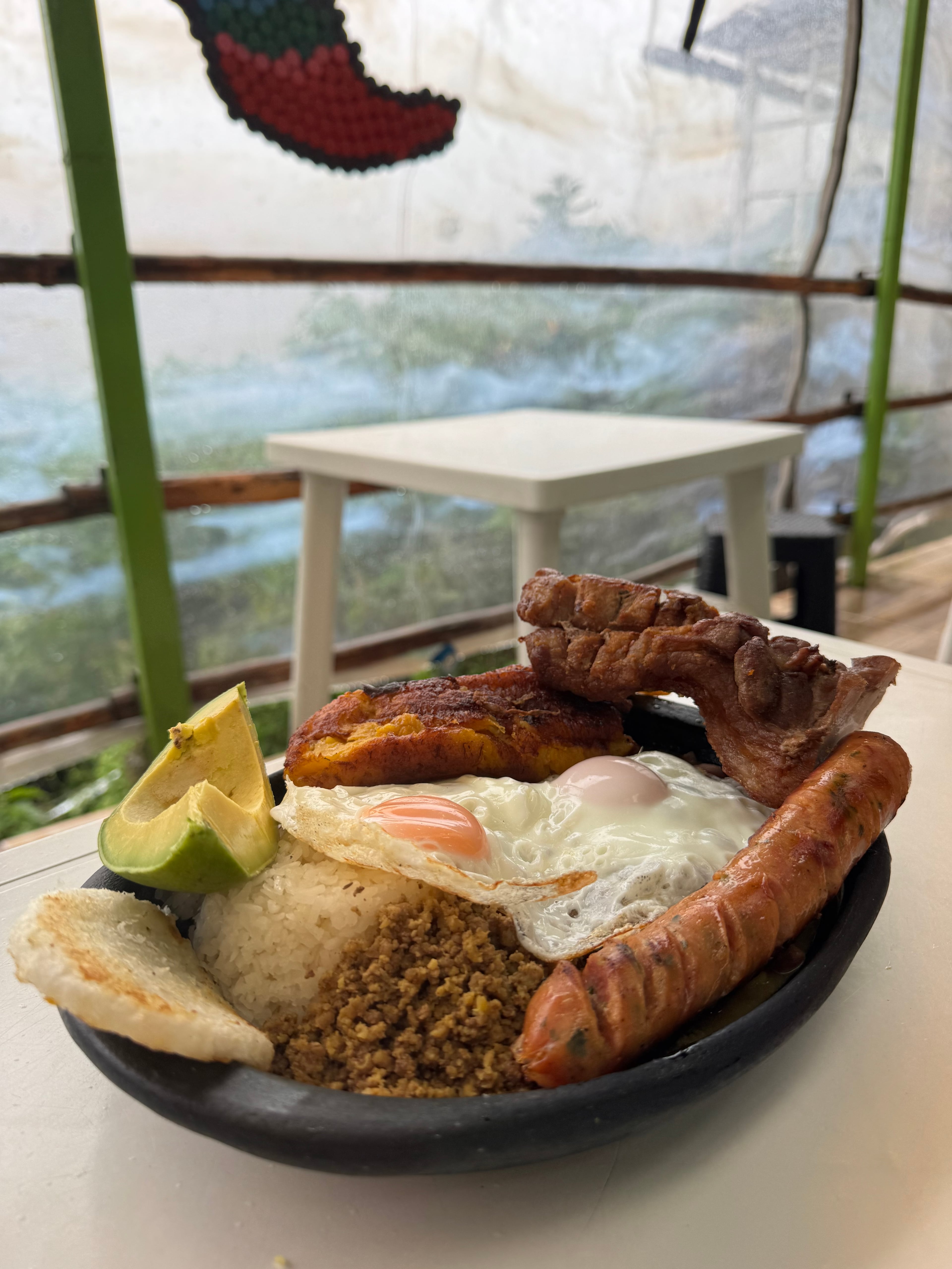 A Colombian bandeja paisa with avocado, plantain, eggs, sausage, and pork.