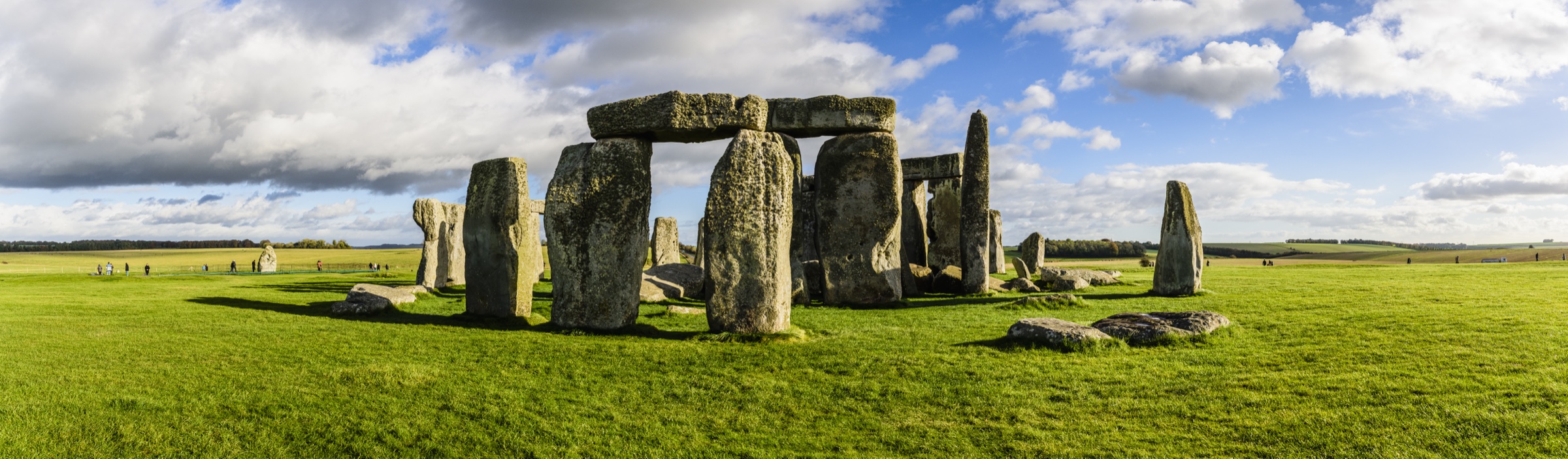 Stonehenge standing stones in a wide green field.