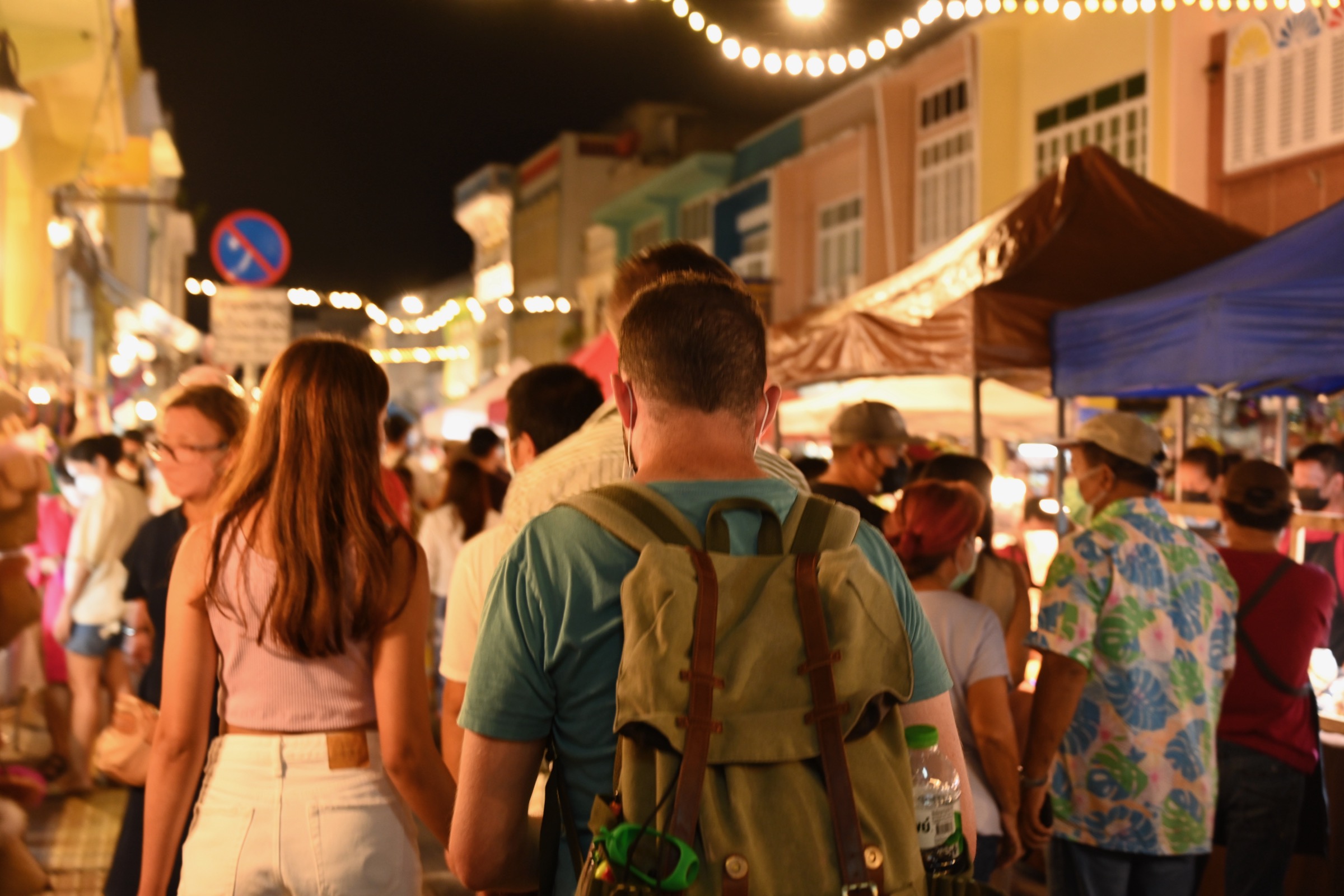 Crowds moving through a night market in Thailand beneath warm stall lights.